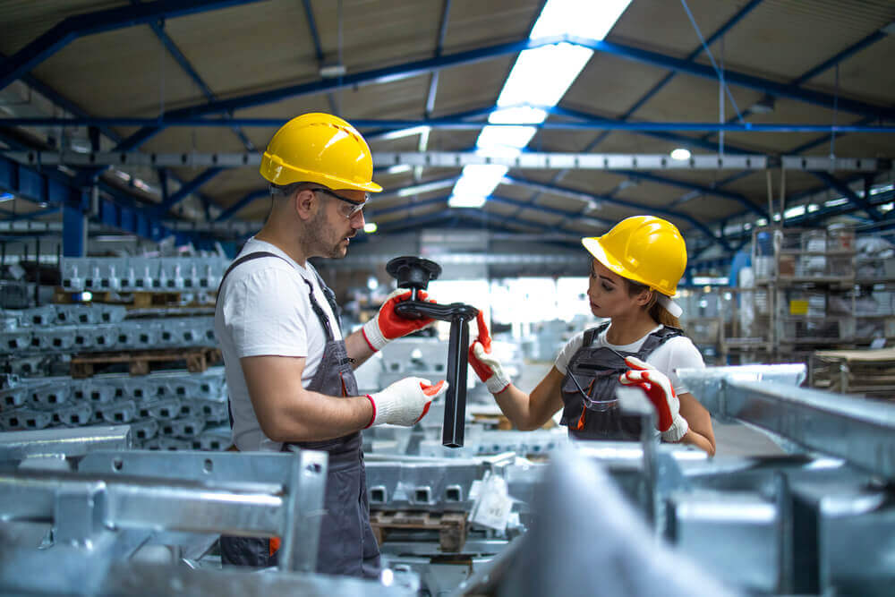 Two people working on a part in a factory