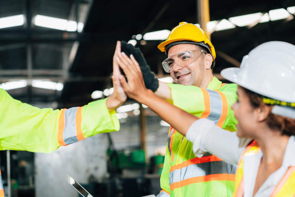 Group of people high-fiving in a factory